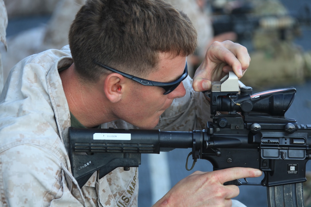 A 26th Marine Expeditionary Unit force reconnaissance Marine checks his scope during a rifle battle sight zero exercise with a M4 Carbine Rifle on the flight deck of USS Kearsarge, Sept. 1, 2010. 26th MEU deployed aboard the ships of Kearsarge Amphibious Ready Group in late August responding to an order by the Secretary of Defense to support Pakistan flood relief efforts.