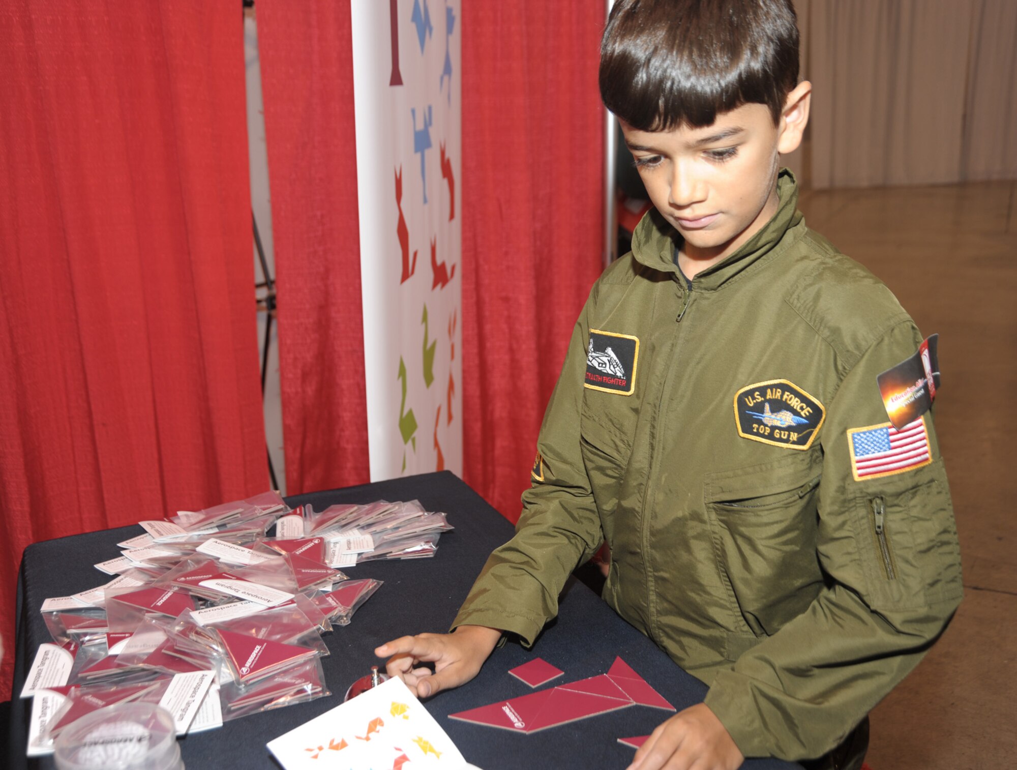 A future Airman builds a rocket out of puzzle pieces at the jointly manned SMC and Aerospace Corporation booth in Education Alley at the AIAA Space 2010 conference, Sept.1.  The puzzle is called a tangram, which consists of seven flat pieces used to form shapes. (Photo by Joe Juarez) 