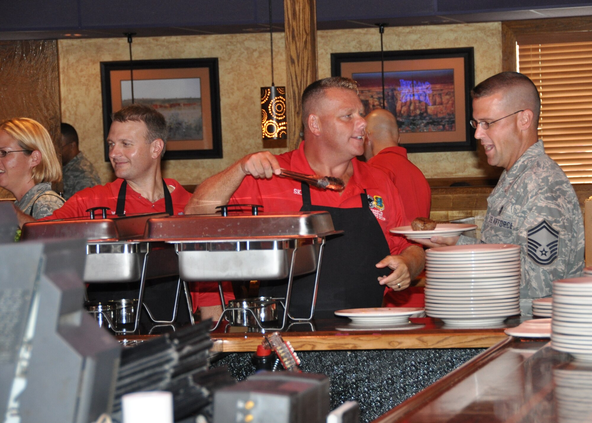 Chief Master Sgt. Michael Skidmore, left, serves a steak to Senior Master Sgt. Jason Devereaux Aug. 27 at the Outback Steak House in D’Iberville during the annual Keesler Chiefs Group steak sale.  Chief Skidmore and Sergeant Devereaux are from the 81st Aerospace Medicine Squadron.  The proceeds support various base activities for Keesler Airmen, including Airman Leadership School and NCO Academy graduations.  (U.S. Air Force photo by Kemberly Groue)