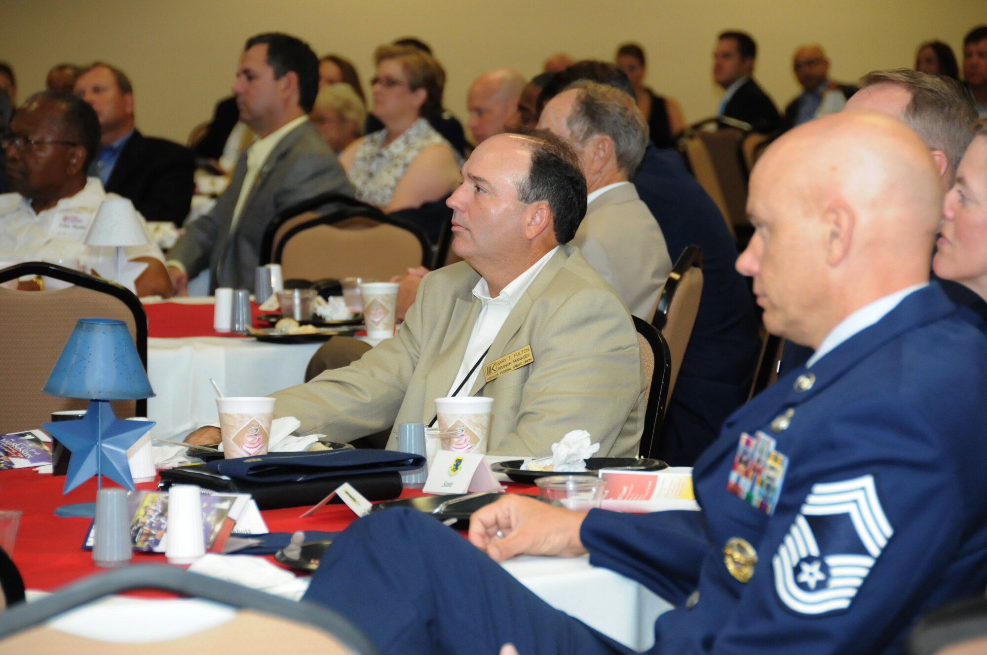 Gary Fulton, center, and Chief Master Sgt. Billy Abbott listen to remarks from Brig. Gen. Andrew Mueller, 81st Training Wing commander, at the Biloxi Chamber of Commerce Morning Call, Aug. 25 at the Dragon’s Lair. Mr. Fulton is manager of Keesler Federal Credit Union’s Larcher Branch and Chief Abbott is superintendent of the 81st Training Group. The Morning Call is a quarterly gathering of civic leaders sponsored by area businesses and organizations.  (U.S. Air Force photo by Kemberly Groue)