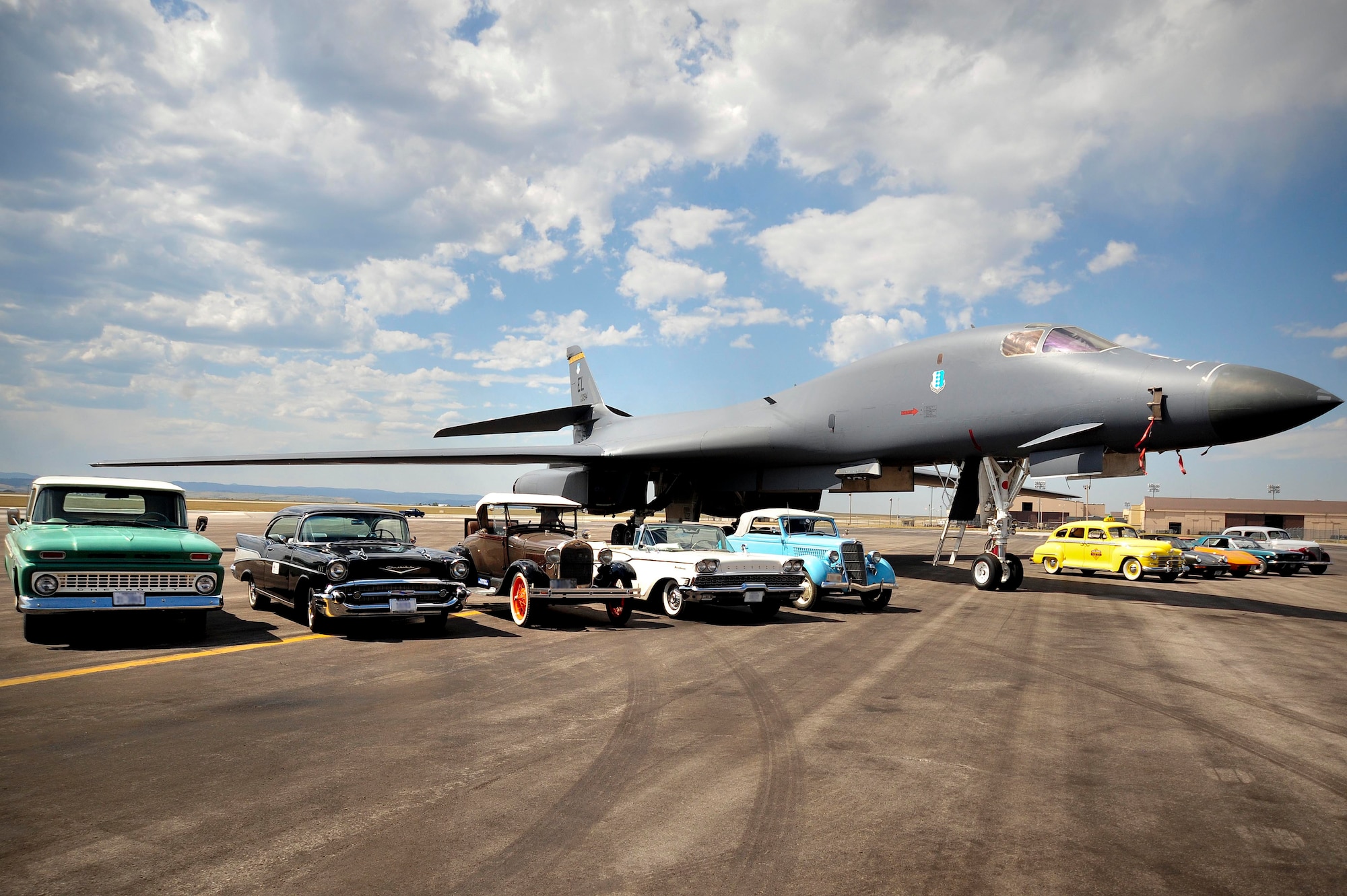 ELLSWORTH AIR FORCE BASE, S.D. - Vehicles from the Rollin’ Oldies Car Club park next to a B-1B Lancer during a base tour, Aug. 27. Rollin’ Oldies Car Club members experienced a firsthand look of Ellsworth Air Force Base and various squadron demonstrations during their tour. (U.S. Air Force photo/Senior Airman Corey Hook)