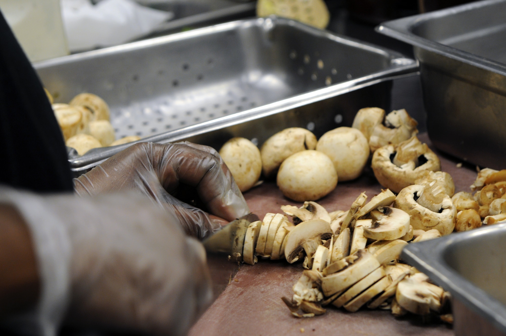 A food service worker chops mushrooms Aug. 23 for the salad bar at the Hercules Dining Facility. The salad bar offers a healthier dining option for warfighters. (Courtesy photo by Ashley Mangin)