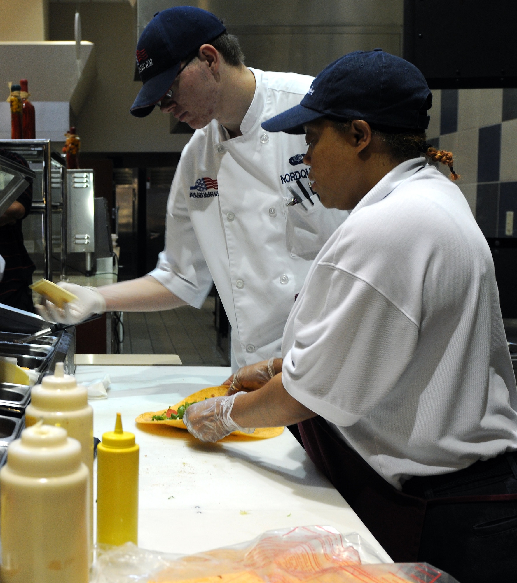 Barbie Jackson (foreground) and Airman 1st Class Larry Nordquest, both 19th Force Support Squadron food service cooks, prepare wraps and sandwiches for lunchtime meals Aug. 23 at the Hercules Dining Facility. The dining facility opened at its current location in October 2009 and has served more than 21,500 meals each month to meal card holders and other authorized users. (Courtesy photo by Ashley Mangin)