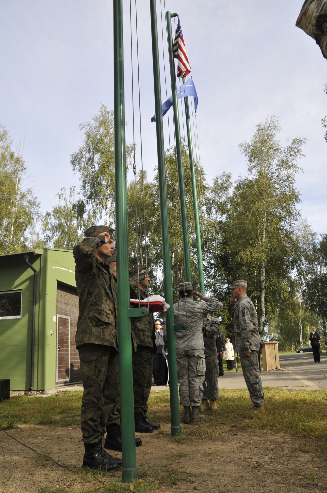 U.S. Air Force Airmen (right) raise the American flag at Lithuania Air Force Air Base, Lithuania, September 1, 2010, as Polish air force airmen hold their flag during the assumption of command ceremony. The 493rd Expeditionary Fighter Squadron assumed command of the four-month mission. (U.S. Air Force photo/Tech. Sgt. Christopher Stagner)