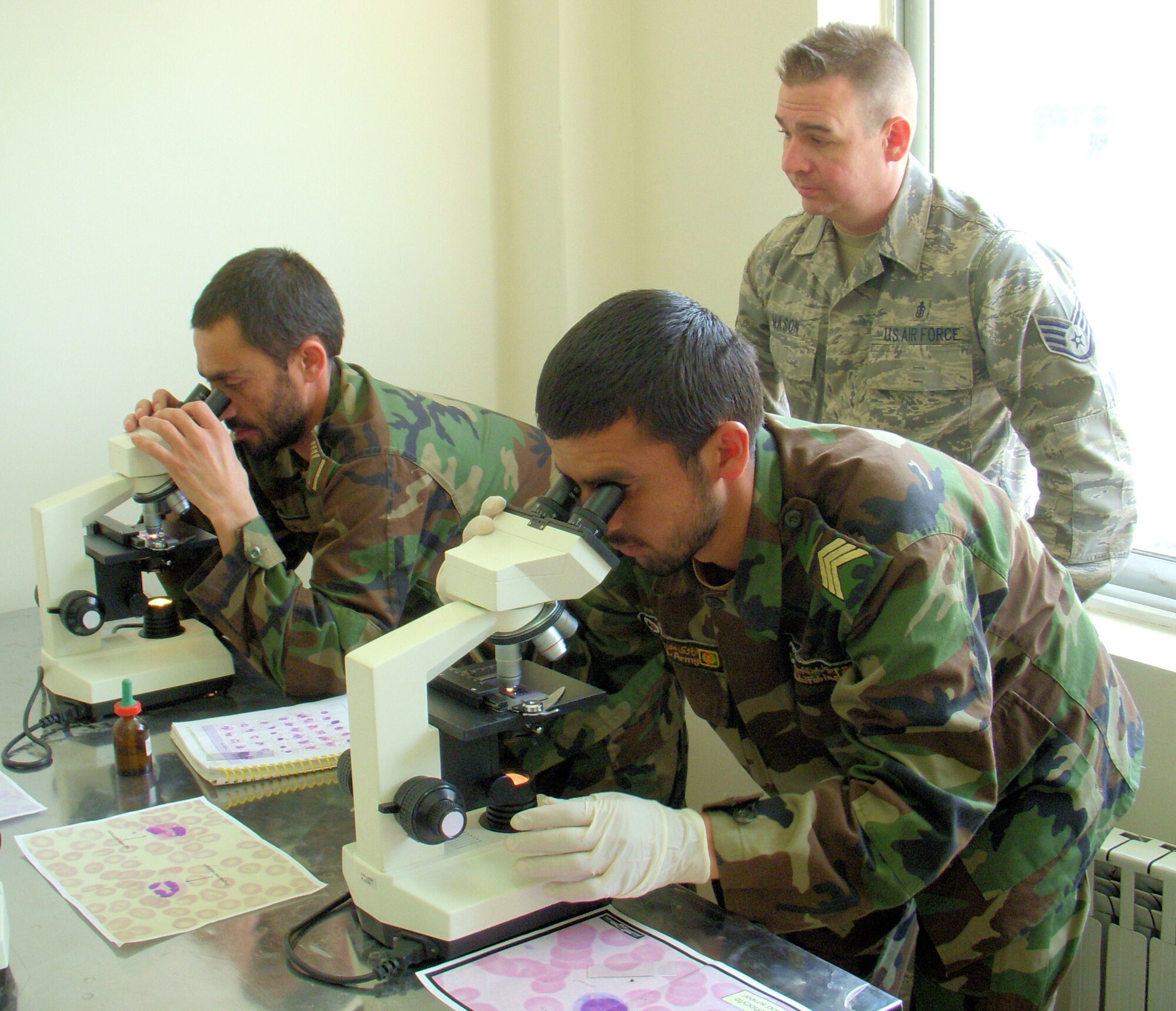 KABUL, Afghanistan -- Staff Sgt. Cole Mason, a medical embedded training team member, provides Afghan students in the Allied Health Professional's Institute near Camp Eggars, Afghanistan, hands-on instruction with microscopes. Sergeant Mason instructed a class of 20 Afghan National Guard and Afghan National Police for six months regarding laboratory procedures and practices. (Air Force courtesy photo)