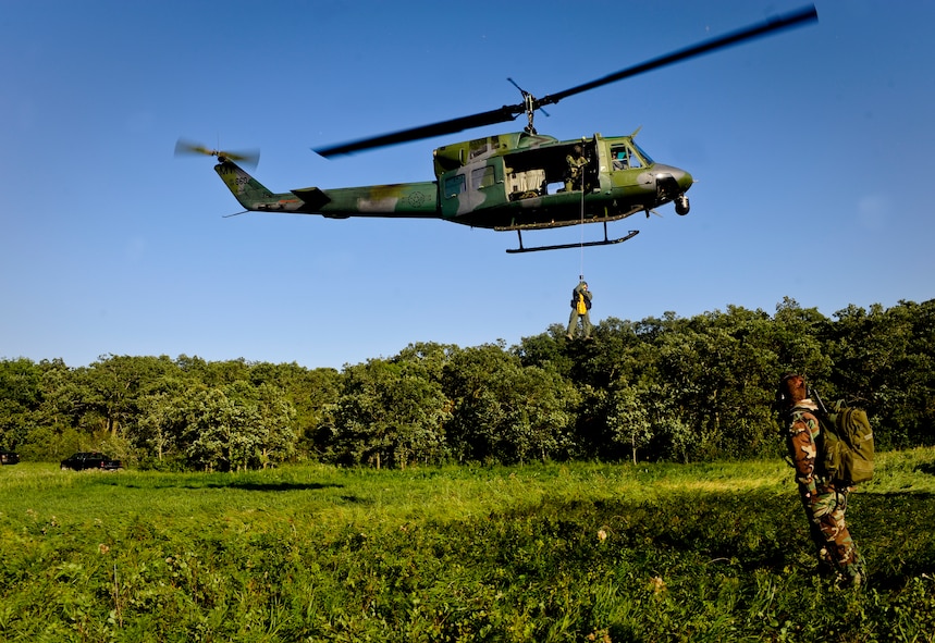 SOMEWHERE IN THE TURTLE MOUNTAINS, N.D. -- Aircrew members of the 54th Helicopter Squadron practice extraction techniques as they are hoisted to a UH-1N Huey during a two-day survival, evasion, resistance and escape refresher course here Aug. 25. The course, led by Staff Sgt. Brett Sipe, 5th Operations Support Squadron base SERE instructor, focused only on the evasion and survival portions of the training. (U.S. Air Force photo by Senior Airman Benjamin Stratton)