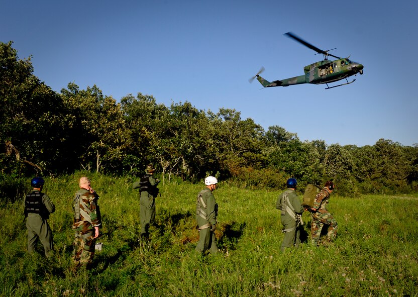 SOMEWHERE IN THE TURTLE MOUNTAINS, N.D. -- Aircrew members of the 54th Helicopter Squadron signal a UH-1N Huey to their location during a two-day survival, evasion, resistance and escape refresher course here Aug. 25. The helicopter portion of the course allowed the Rough Riders a chance to brush up on their extraction skills. The course, led by Staff Sgt. Brett Sipe, 5th Operations Support Squadron base SERE instructor, focused only on the evasion and survival portions of the training. (U.S. Air Force photo by Senior Airman Benjamin Stratton)