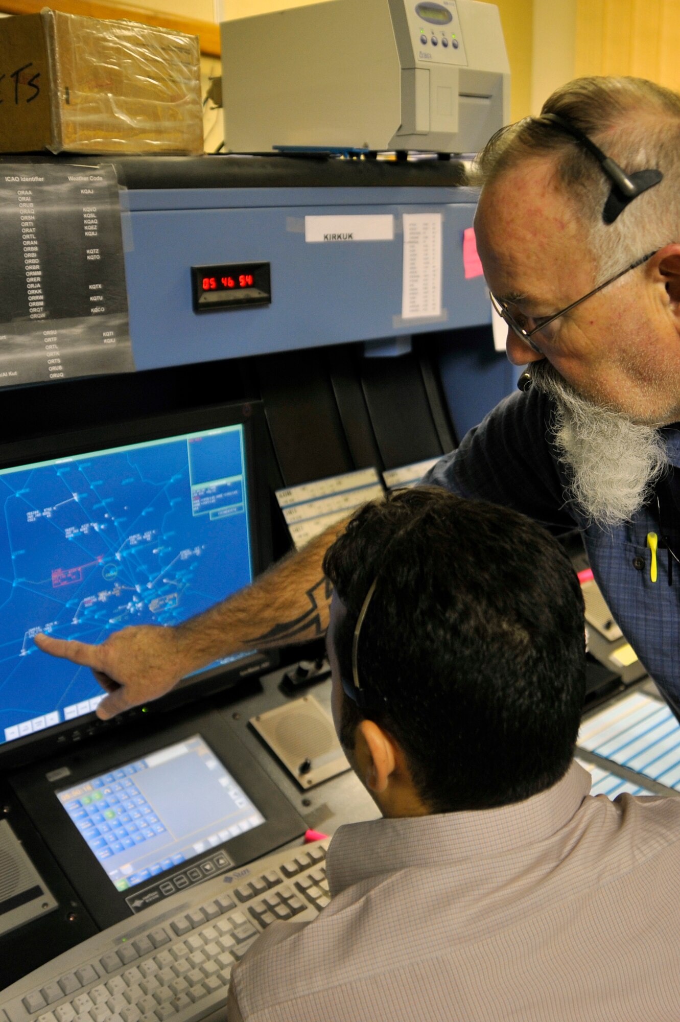 Tom Samples, Washington Consulting Group, air traffic controller trainer and retired Federal Aviation Administration controller, advises an Iraqi air traffic controller, directing the airspace of aircraft traveling through Iraq, Aug. 31, 2010, at Baghdad International Airport. Mr. Samples is contracted by the Iraq Civil Aviation Authority to train and advise Iraqi controllers. With help from the Air Component Coordination Element - Iraq air space planners. As Part of Operation New Dawn, and the Strategic Framework Agreement, the U.S. Air Force is turning over airspace control from 15,000 to 24,000 feet in the northern sector of Iraq-known as the Kirkuk sector. (U.S. Air Force photo by Senior Airman Perry Aston) (Released)