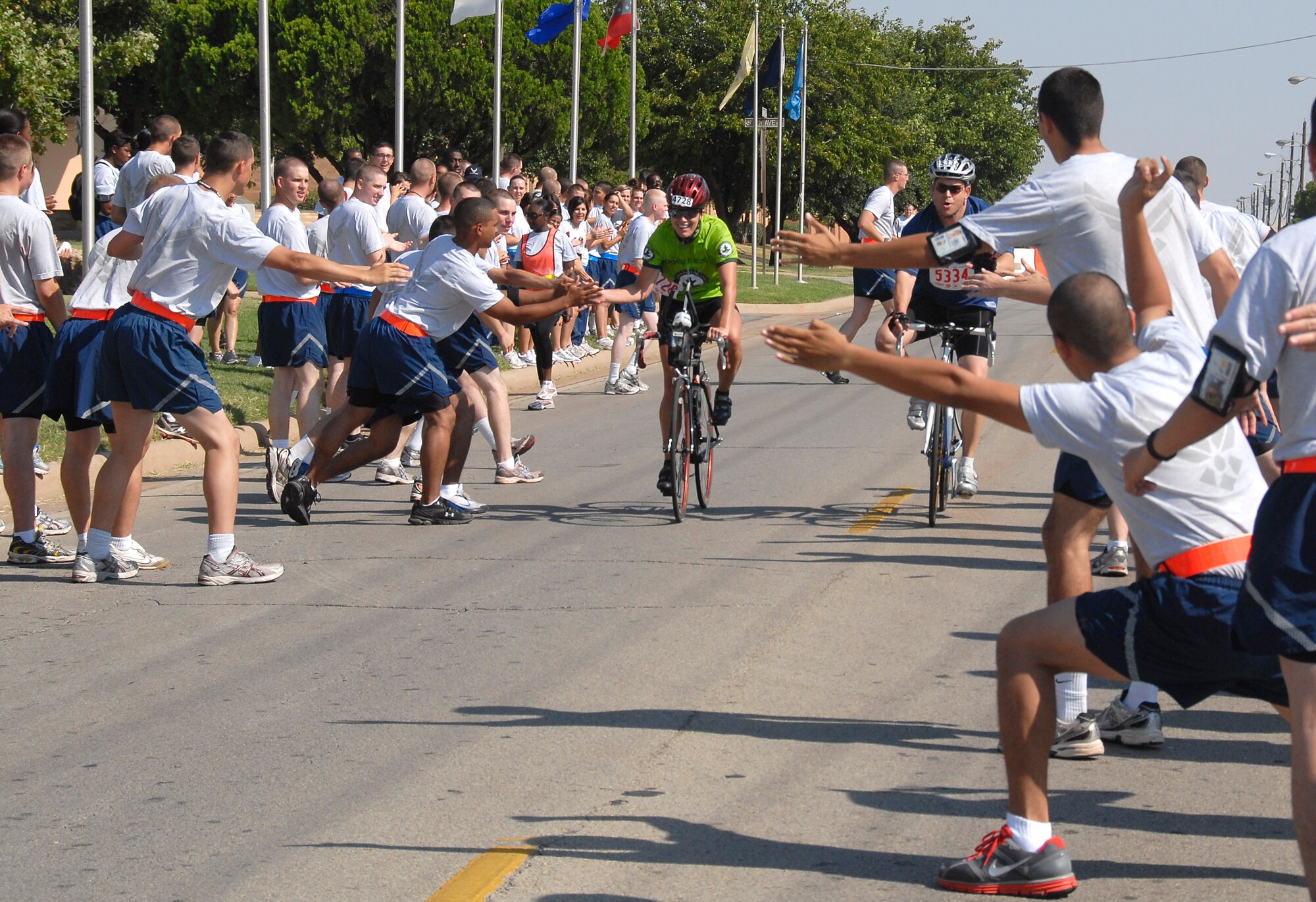 Airmen in Training cheer for Hotter ‘n Hell Hundred riders Aug. 28 as they pass through one of the final segments of their route through Sheppard Air Force Base, Texas.  More than 200 Airmen lined both sides of the road and cheered enthusiastically for every rider that passed through AiT Alley.  (U.S. Air Force photo/Mike Litteken)