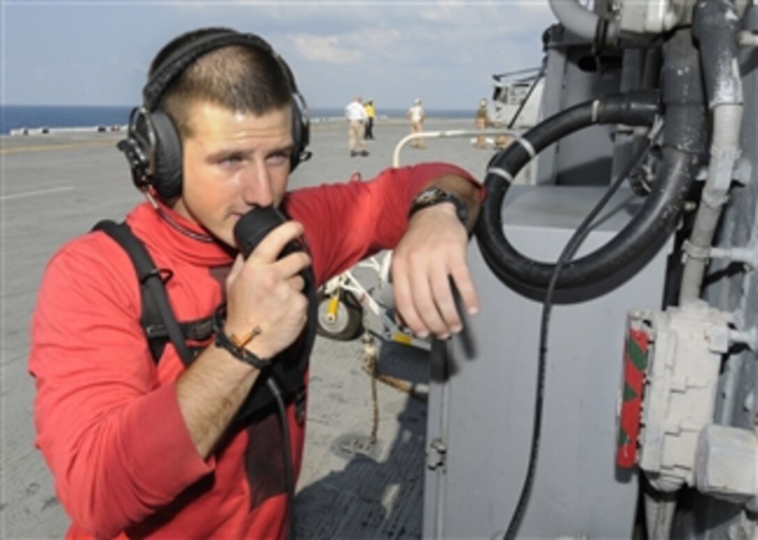 U.S. Navy Petty Officer Chase Hickman checks a phone on the flight deck of the amphibious assault ship USS Kearsarge (LHD 3) in the Atlantic Ocean while the ship is on its way to provide relief to flooded areas of Pakistan on Aug. 28, 2010.  