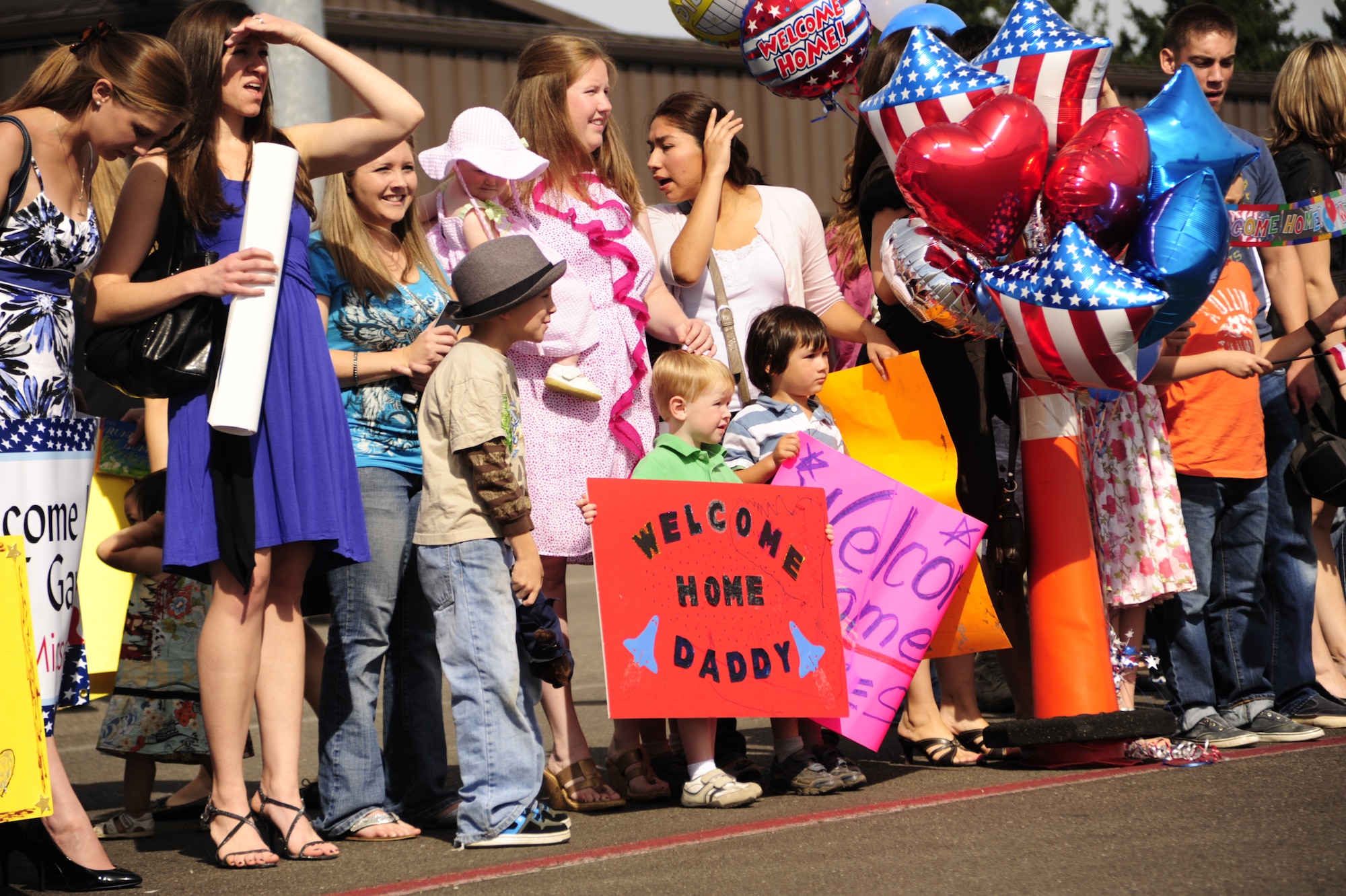 Smiling families and friends wait for Airmen assigned to the 8th Airlift Squadron to return from a four-month deployment Sept. 2 at Joint Base Lewis-McChord, Wash. The squadron deployed as the 816th Expeditionary Airlift Squadron in support of Operation NEW DAWN, formerly IRAQI FREEDOM. (U.S. Air Force photo/Airman Leah Young)