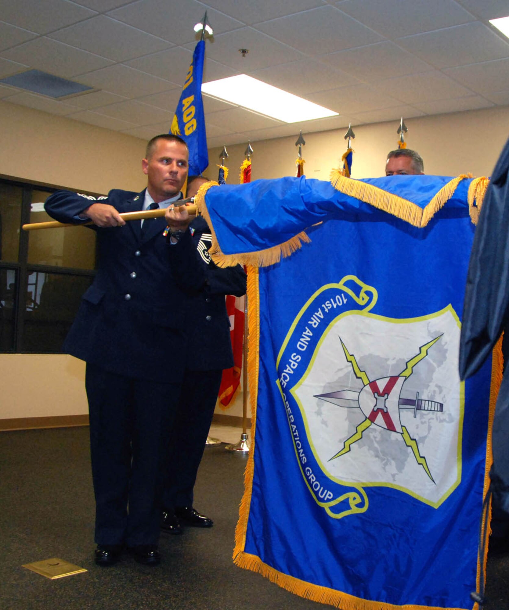 Chief Master Sgt. Lynn Boop, the 101st Air and Space Operations Group chief enlisted manager, unfurls the unit’s organizational flag Aug. 21, 2010, during a ceremony at Tyndall Air Force Base, Fla., to commemorate the activation of the 101st AOC.  (U.S. Air Force photo/Capt. Jared Scott)