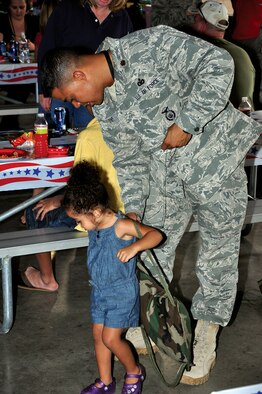 Maj. Melvin Turner, 90th Security Forces Squadron, helps his daughter put on a backpack during the Deployed Airman Barbecue held in the base lakes pavilion on Friday. (U.S. Air Force photo by Staff Sgt. Chad Thompson)