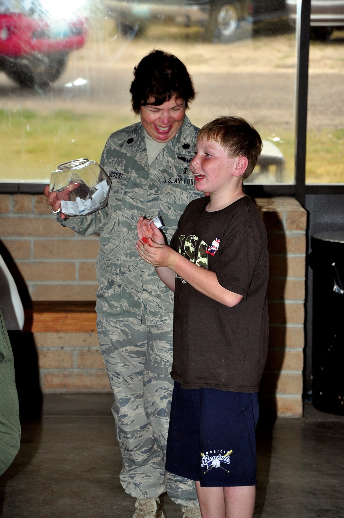 Lt. Col. Joanne Ruggeri, 90th Medical Operations Squadron, assists a youth in calling names out for the raffle during the Deployed Airmen Barbecue. (U.S. Air Force photo by Staff Sgt. Chad Thompson)