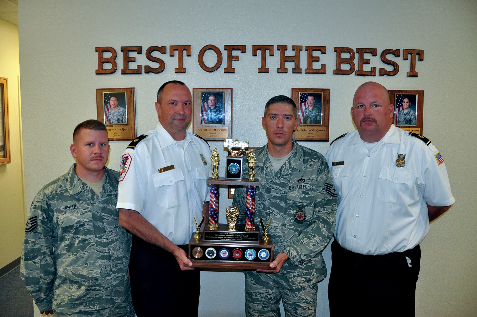 Tech Sgt. John Smith, fire chief John MacDougall, Tech Sgt. Michael Falzone and assistant fire chief Greg Chesser, all part of the 90th Civil Engineer Squadron, pose for a photo in the fire station on Tuesday while holding the Department of Defense Fire and Emergency 2009 Fire Department of the Year small-unit Award. (U.S. Air Force photo by Airman 1st Class Daniel Gage)