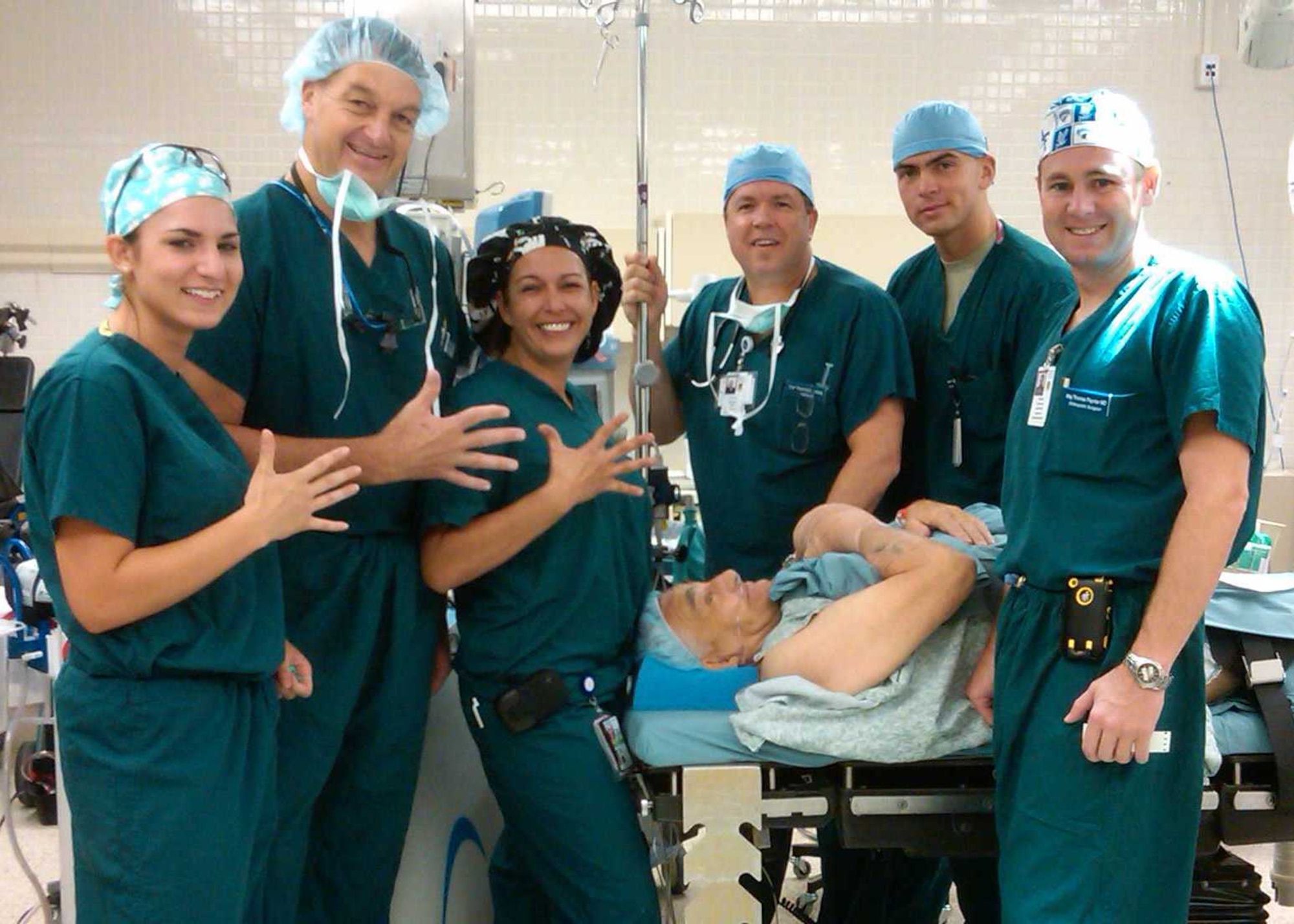 Members of an 81st Medical Group orthopedic surgical team display five fingers as a two-fold symbol following completion of an Aug. 19 surgical procedure.   Surgery technician Senior Airman Christine Villarreal, left, orthopedic surgeon Brig. Gen. (Dr.) Kory Cornum, 81st Medical Group commander, and operating room nurse Ms. Missy Allen hold up their hands to signify Airman Villarreal’s selection for promotion to staff sergeant (E-5).  The other members of the OR team are, from left, certified registered nurse anesthetist Capt. Richard Huff, surgery technician Airman 1st Class Karol Kowalczuk and orthopedic surgeon Maj. (Dr.) Thomas Paynter.  The team was performing hand surgery on retired Air Force Tech. Sgt. Ronald Bogart when the staff sergeant list was released at 8 a.m.  The scrub nurse checked the computer in the OR for the promotion list and showed everyone the great news.  This was Airman Villarreal’s first time eligible for staff sergeant.  The hand surgery also marked General Cornum’s first elective surgery case since becoming Group commander.  He had performed emergency surgery a few weeks prior while serving as the on-call orthopedic surgeon for the medical center.  The general sees patients in the clinic every week and operates as often as he finds patients needing surgery.  The other team members are assigned to the 81st Surgical Operations Squadron.

