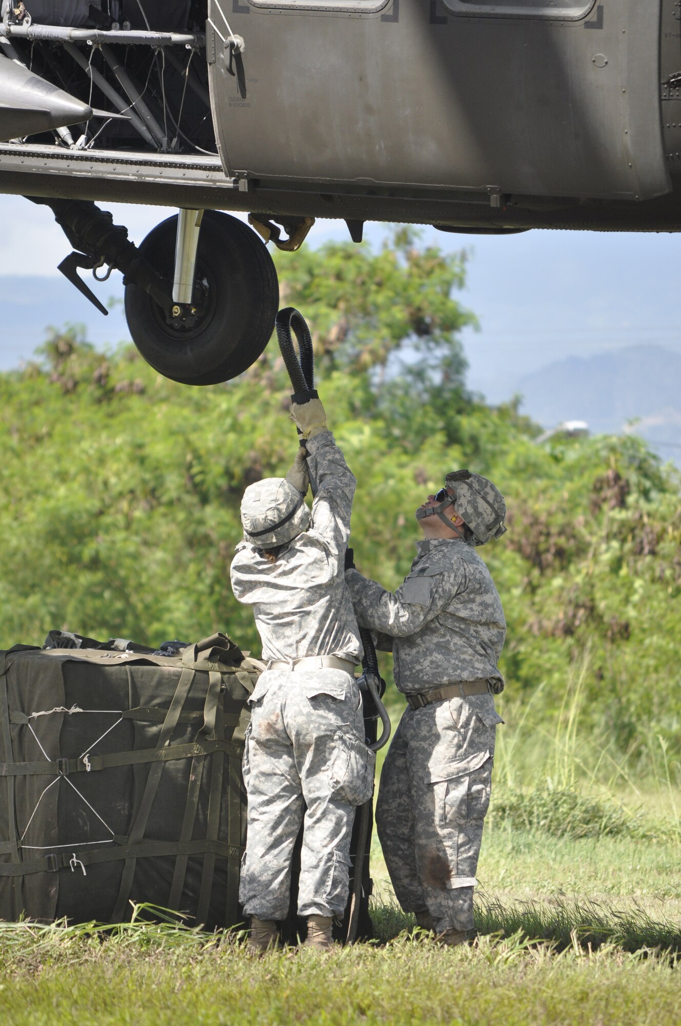 SOTO CANO AIR BASE, Honduras --  Spc. Peggi Williams, left, with J4, and Staff Sgt. Eugenio Gonzalez, with Army Forces, work to hook cargo to a helicopter during sling load training here Sept. 1. In case of humanitarian or disaster relief efforts to areas not accessible by convoy, ARFOR personnel will rig cargo to helicopters for transport. (U.S. Air Force photo/Martin Chahin)