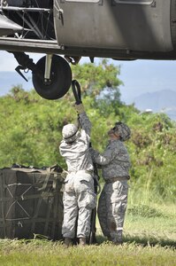 SOTO CANO AIR BASE, Honduras --  Spc. Peggi Williams, left, with J4, and Staff Sgt. Eugenio Gonzalez, with Army Forces, work to hook cargo to a helicopter during sling load training here Sept. 1. In case of humanitarian or disaster relief efforts to areas not accessible by convoy, ARFOR personnel will rig cargo to helicopters for transport. (U.S. Air Force photo/Martin Chahin)