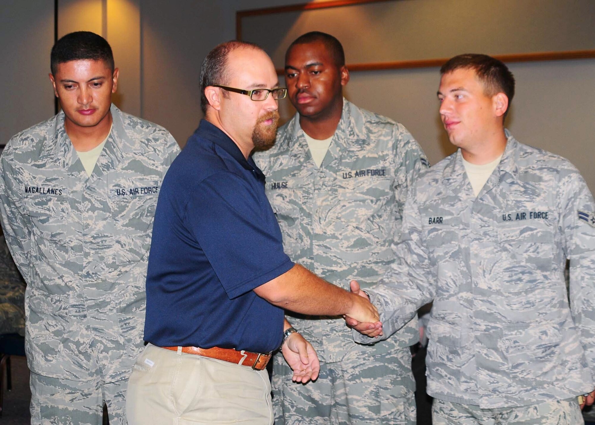 Mr. David Wallace presents the new environmental coin from the 97th Civil Engineer Squadron to Staff Sgt. Pedro Magallanes, Airman 1st Class Andre Hulse, and Airman 1st Class Corey Barr among others at the CES Commander's Call September 1. The environmental coin recognizes outstanding achievers in Environmental stewardship and conservation. (U.S. Air Force photo, Tech. Sgt. Jennifer Seidl / Release 97th Air Mobility Wing Public Affairs)