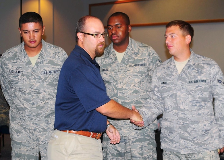 Mr. David Wallace presents the new environmental coin from the 97th Civil Engineer Squadron to Staff Sgt. Pedro Magallanes, Airman 1st Class Andre Hulse, and Airman 1st Class Corey Barr among others at the CES Commander's Call September 1. The environmental coin recognizes outstanding achievers in Environmental stewardship and conservation. (U.S. Air Force photo, Tech. Sgt. Jennifer Seidl / Release 97th Air Mobility Wing Public Affairs)