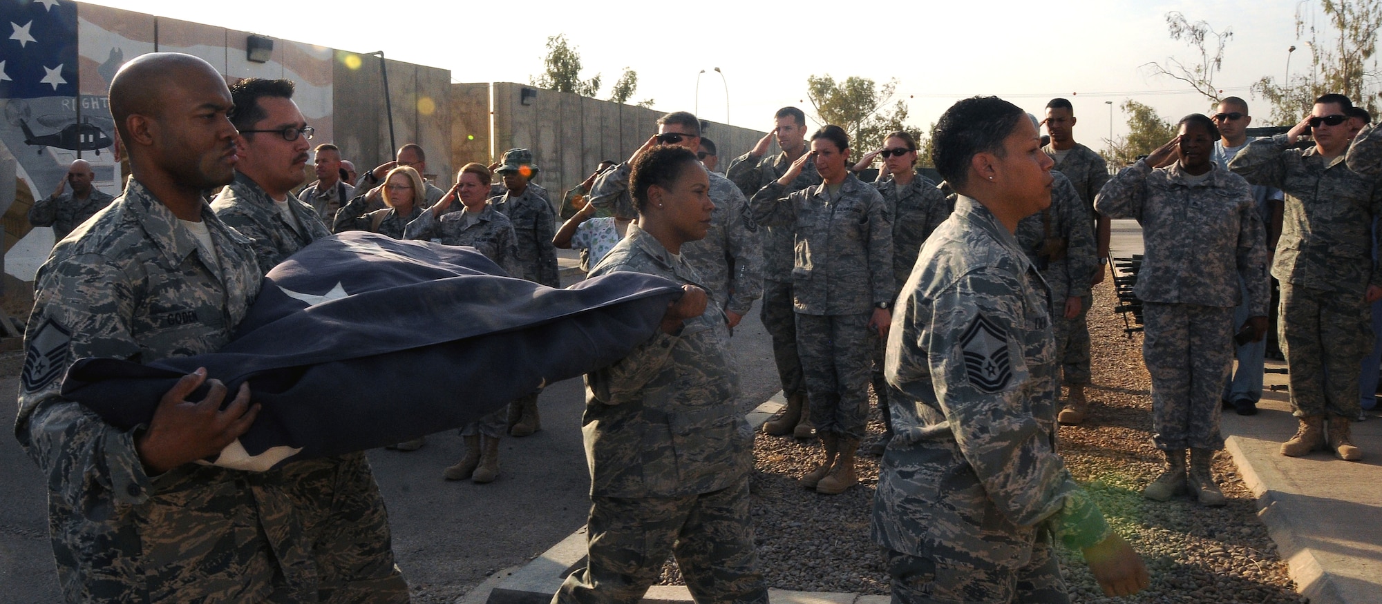 Members of the 332nd Expeditionary Medical Group render a salute to the folded American flag that hung above Hero’s Highway prior to Operation New Dawn Sept 1, 2010, Joint Base Balad, Iraq.  Members of the 332 EMDG took a moment to think about what that flag had witnessed in the past – and what it could witness in the future. (U.S. Air Force photo/Senior Airman Marianne E. Lane)