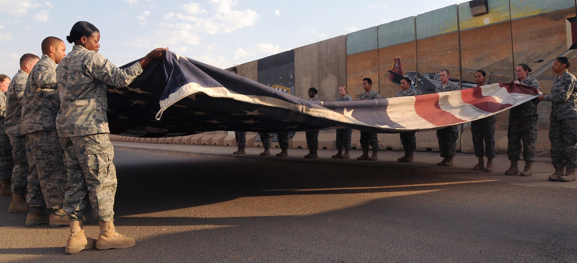 Members of the 332nd Expeditionary Medical Group Color Guard prepare to fold the American Flag at Hero’s Highway Sept. 1, 2010, Joint Base Balad, Iraq. The 20-by-30-foot flag serves as a visual assurance for wounded U.S., Iraqi and coalition service members as they enter the hospital.  (U.S. Air Force photo/Senior Airman Marianne E. Lane)