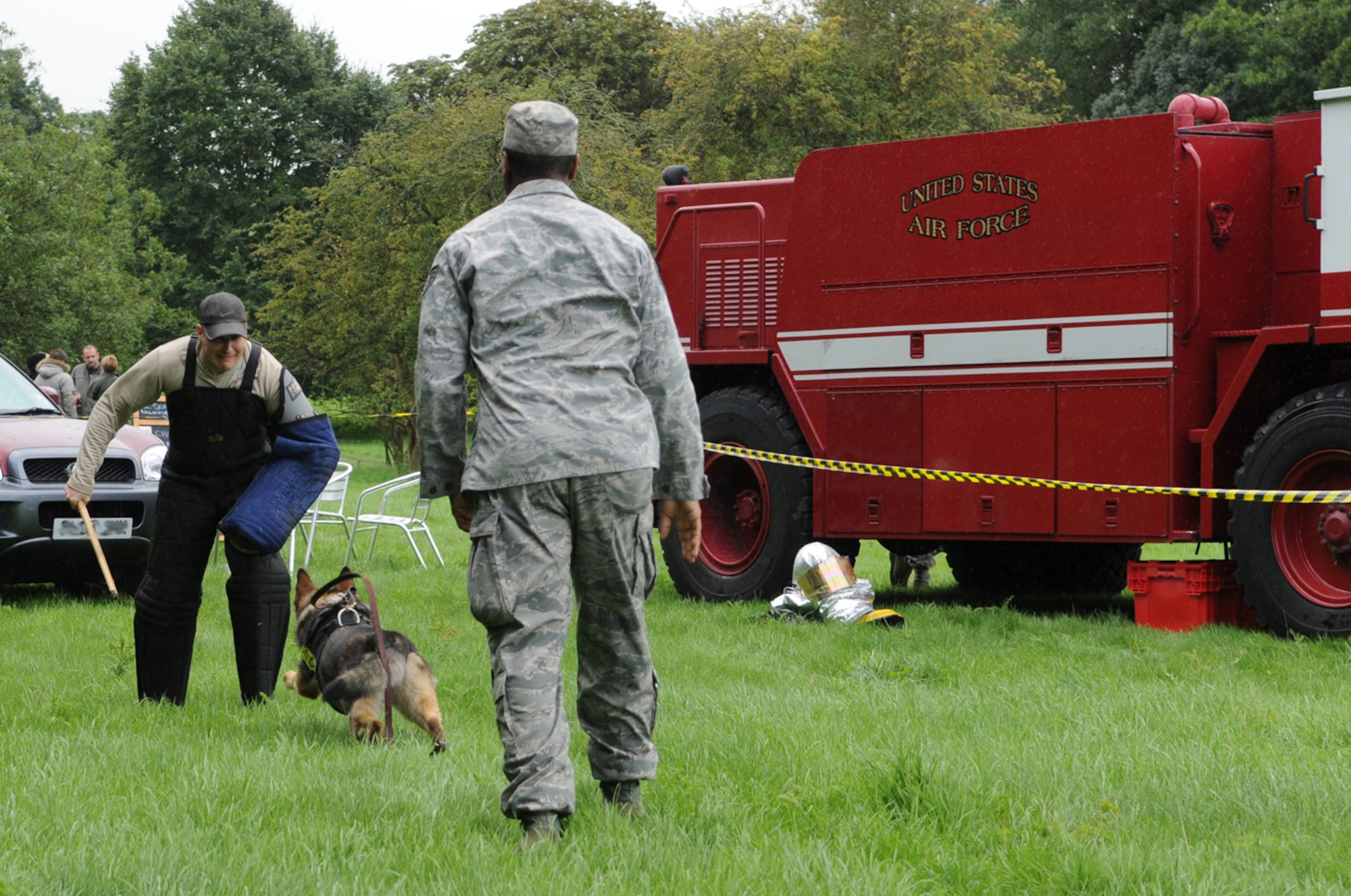 RAF MILDENHALL, England -- Military Working Dog Gina, 100th Security Forces Squadron, prepares to "attack" mock aggressor, Staff Sgt. Grant Champeaux, 100th SFS MWD section, as her handler, Staff Sgt. Billy Loftus, quickly follows her to call her off when necessary. MWDs Gina and Zulton, along with Airmen from the section, took part in a training demonstration at a charity event in Icklingham, near Bury St. Edmunds, Aug. 29. Members from the 100th SFS, along with three members from the RAF Mildenhall Fire Department, took part in the event -- which was held to raise money for the East Anglian Air Ambulance -- despite the heavy rain which kept many potential stall-holders and audience members away. (U.S. Air Force photo/Karen Abeyasekere)