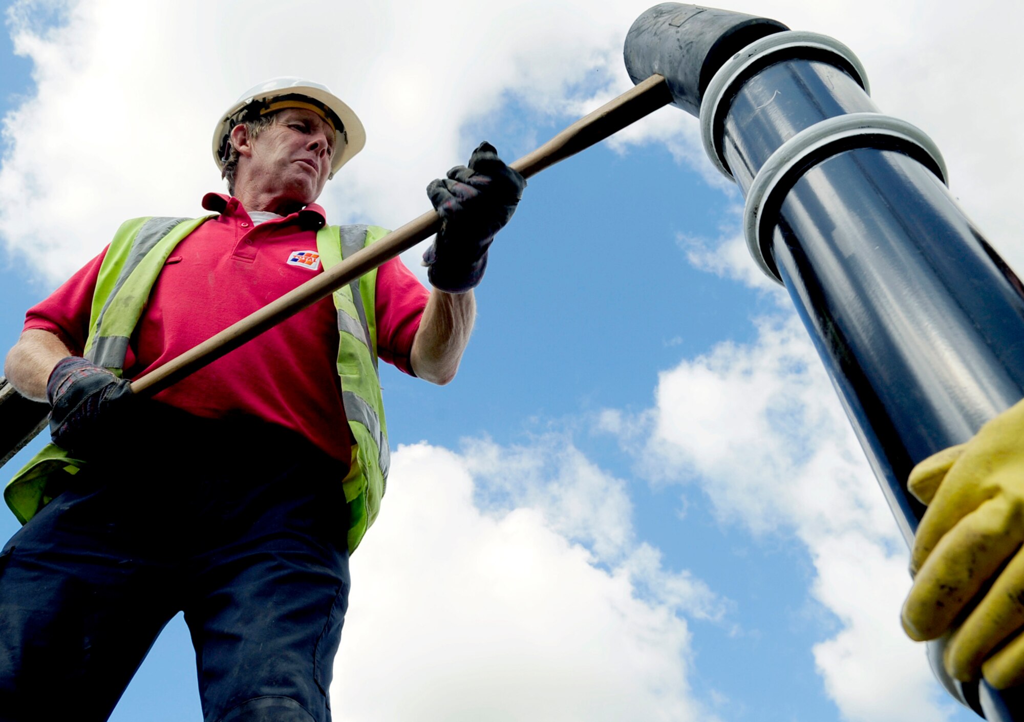 RAF MILDENHALL, England -- David Dodge, a local contractor, hammers a bollard into place to match it with others recently installed in the area here Aug. 31. The bollards are being installed as a force protection measure across the base. (U.S. Air Force photo/Senior Airman Ethan Morgan)