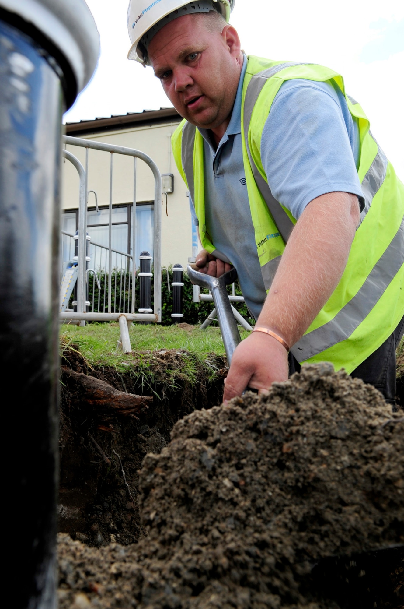 RAF MILDENHALL, England -- Gavin Chapmin, a local contractor, shovels concrete onto the base of a bollard to secure it into place here Aug. 31. These, among other bollards being installed around the base, are part of a new antiterrorism and force protection effort. (U.S. Air Force photo/Senior Airman Ethan Morgan)