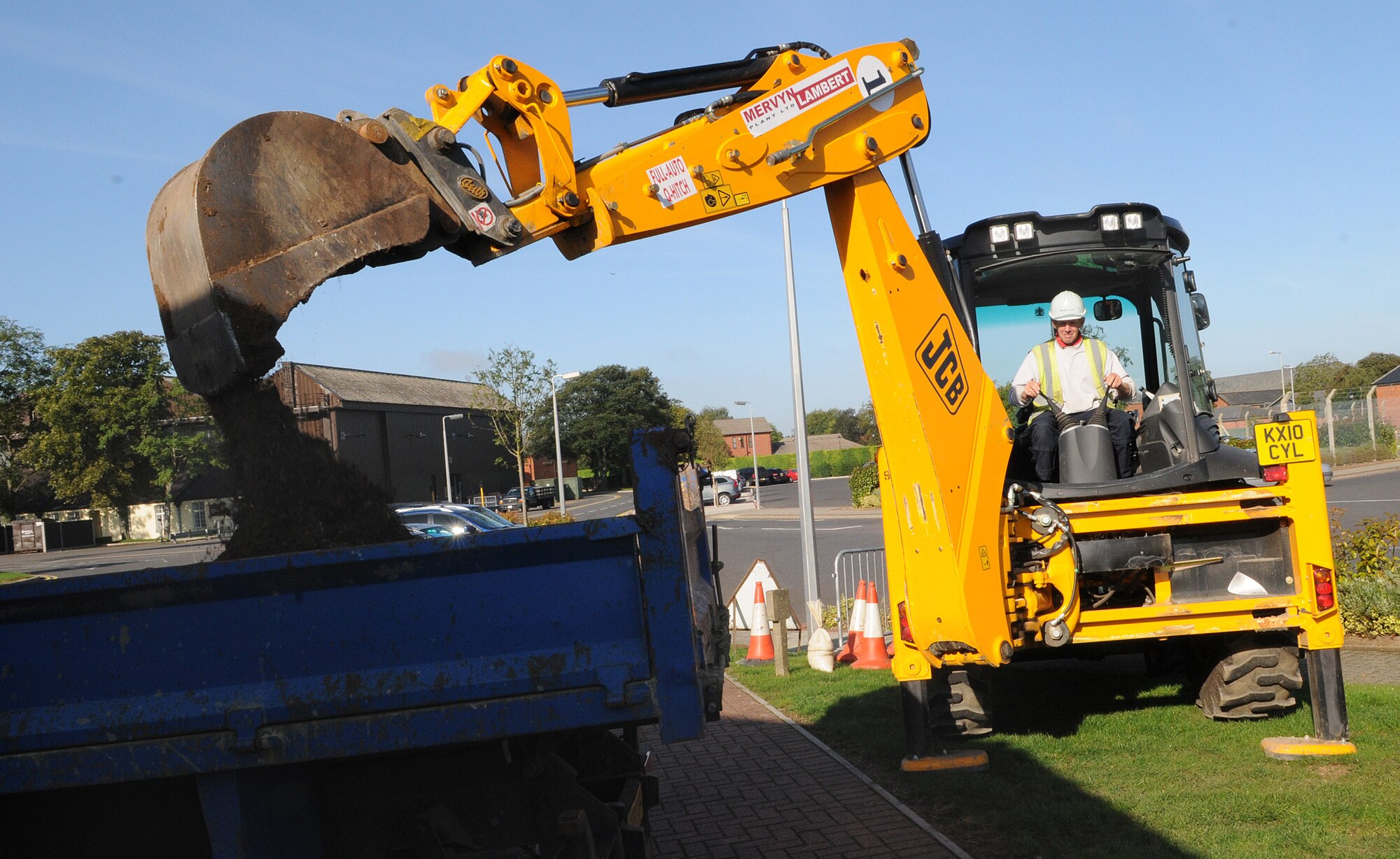 RAF MILDENHALL, England - David Dodge, a local contractor, dumps soil into the back of a truck with a digger here Aug. 31. As part of antiterrorism and force protection measures, security bollards, reinforced with a thick layer of underground cement, are being installed across the base. (U.S. Air Force photo/Staff Sgt. Thomas Trower)