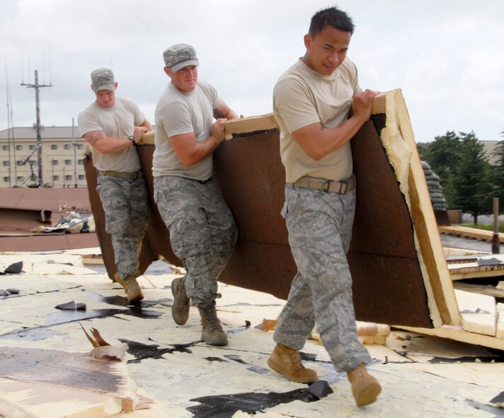 KUNSAN AIR BASE, Republic of Korea -- Senior Airman Garrett Hanson, Staff Sgt. Gerald Bontrager and Senior Airman Ralph Dagza, 8th Civil Engineer Squadron structures shop, carry a piece of broken insulation from a roof Sept. 2 after Typhoon Kompasu swept past Kunsan Air Base. The typhoon caused minimal damage to the base overall. (U.S. Air Force photo/Staff Sgt. Amanda Savannah)