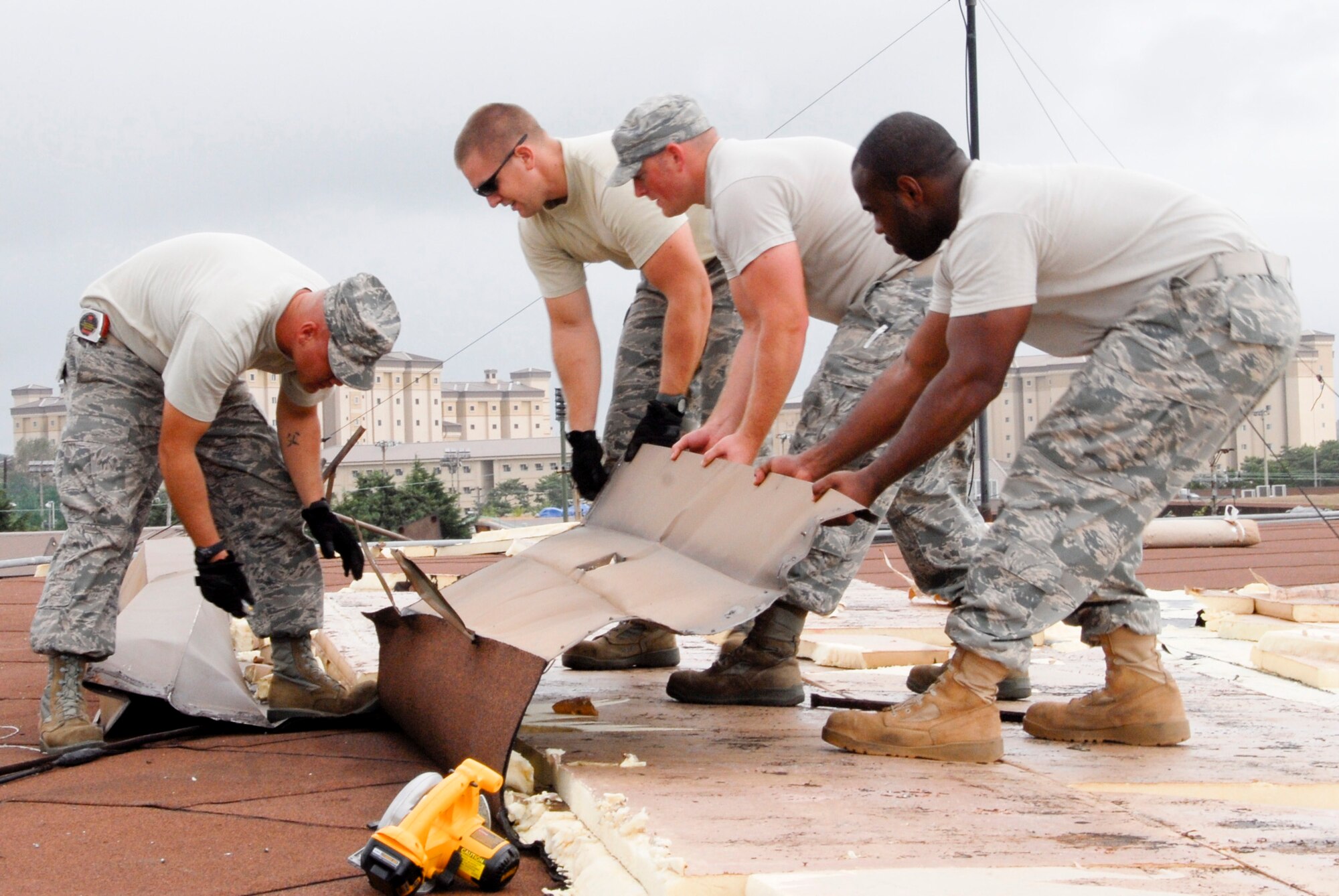 KUNSAN AIR BASE, Republic of Korea -- Staff Sgts. Thomas Agee, Kirk Struss and Gerald Bontrager, 8th Civil Engineer Squadron structures shop, repair shingles on a roof Sept. 2 after Typhoon Kompasu swept past Kunsan Air Base. The typhoon caused minimal damage to the base overall. (U.S. Air Force photo/Staff Sgt. Amanda Savannah)