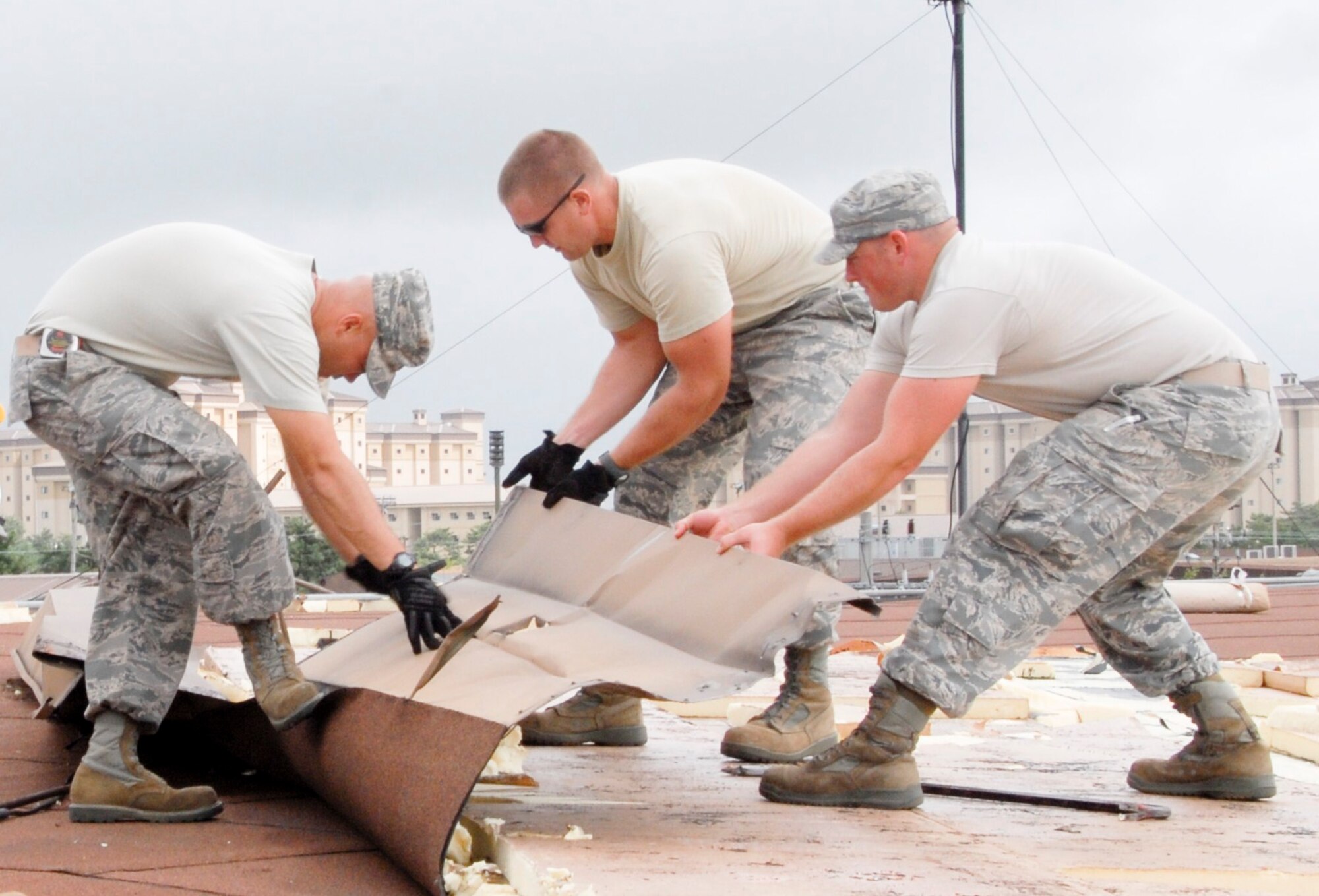 KUNSAN AIR BASE, Republic of Korea -- Staff Sgts. Thomas Agee, Kirk Struss and Gerald Bontrager, 8th Civil Engineer Squadron structures shop, repair shingles on a roof Sept. 2 after Typhoon Kompasu swept past Kunsan Air Base. The typhoon caused minimal damage to the base overall. (U.S. Air Force photo/Staff Sgt. Amanda Savannah)
