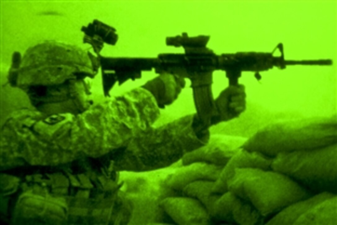As seen through a night-vision device, U.S. Army Sgt. Joseph P. Khamvongsa returns fire against an insurgent attack on Combat Outpost Badel, Afghanistan, Aug. 25. 2010. Khamvongsa, a forward observer, is assigned to Company B, 2nd Battalion, 327th Infantry Regiment.
