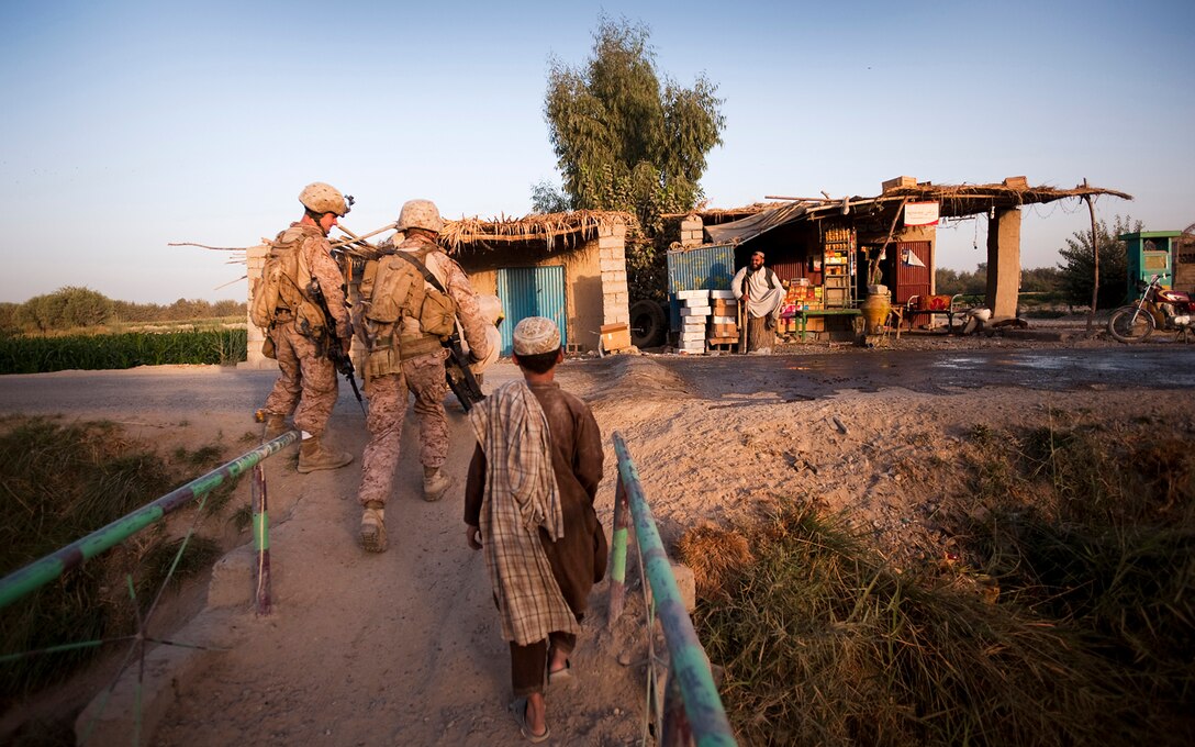 Sgt. Christopher Conaway and Cpl. Curtis Wolf, a squad leader and a team leader with Kilo Company, 3rd Battalion, 3rd Marine Regiment, help an Afghan boy get his wheelbarrow up an incline while manning a vehicle checkpoint as part of security for the Nawa District bazaar in Helmand province, Afghanistan, Sept. 3. The Marines supervise and provide additional security during the checkpoint. Afghanistan National Police officers perform most of the checkpoint duties. Conaway is from Marshall, Mo. Wolf is from Bellevue, Mich.