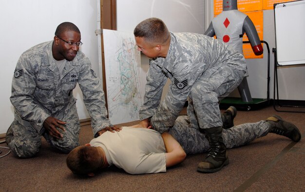 Staff Sgt. Duriel Howard, 8th Security Forces Squadron standardization and evaluation NCO, evaluates Staff Sgt. Jeffrey Tomkiewicz, 8th SFS military working dog handler, on his searching and handcuffing technique. (U.S. Air Force photo/Staff Sgt. Amanda Savannah) 
