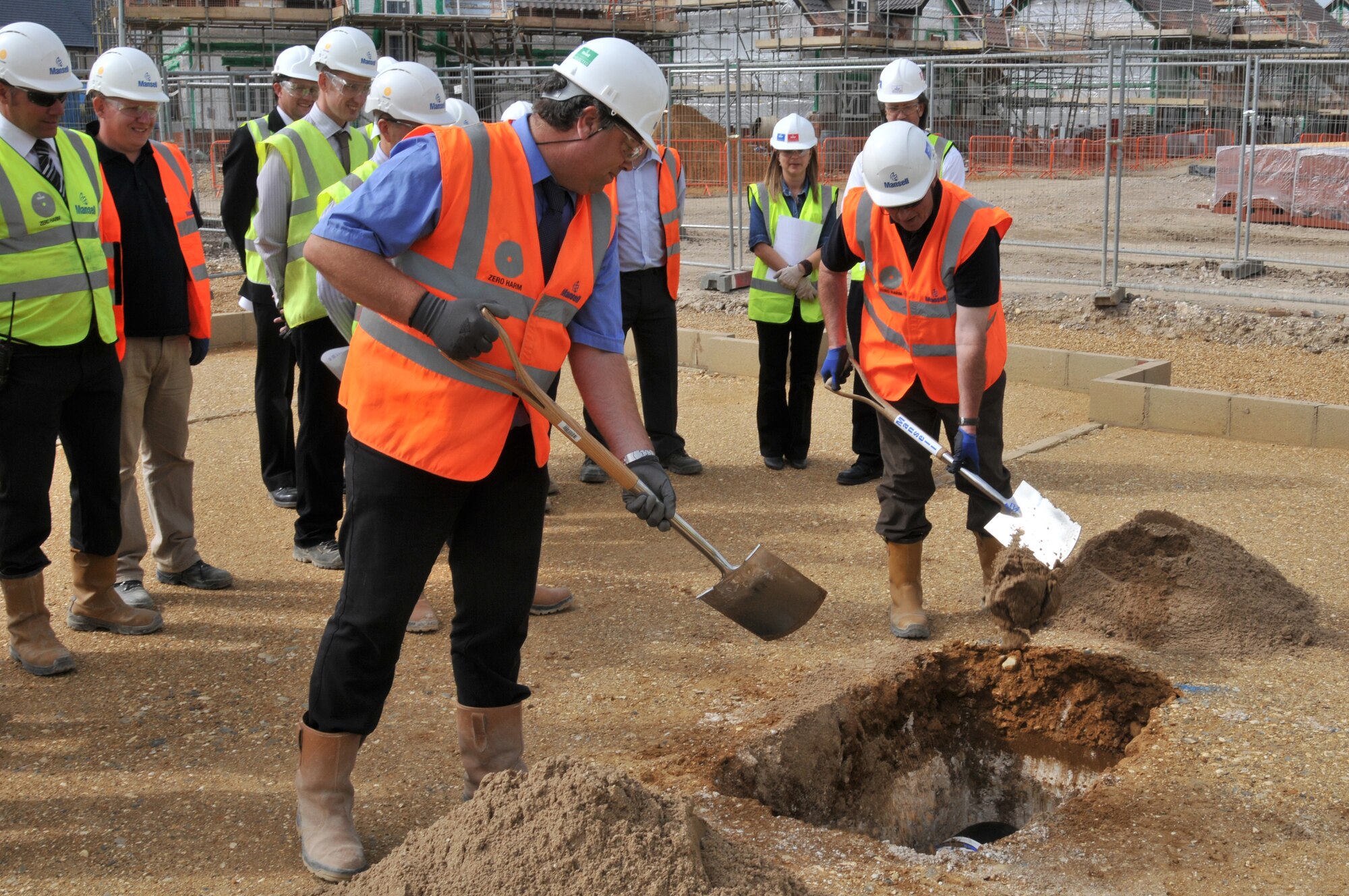 Construction workers fill in the hole containing the Liberty Village time capsule as fellow employees look on Sept. 2, 2010. The capsule was buried below the final foundation to be laid in the Liberty Village Housing project. (U.S. Air Force photo/Senior Airman David Dobrydney)