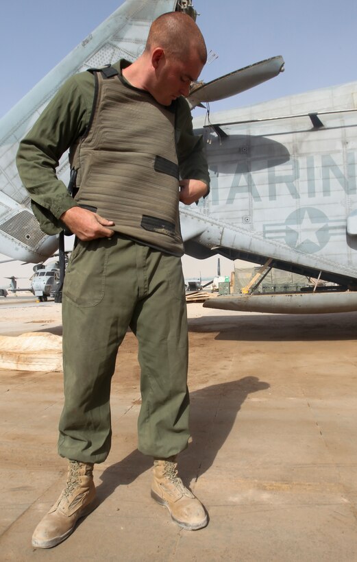 Lance Cpl. Jeffrey Wyman, a flight equipment technician with Marine Heavy Helicopter 361, 3rd Marine Aircraft Wing (Forward), finishes strapping on a Micro Climate Cooling Unit System vest Sept. 4. The vest, made of a thin material laced with hoses that pumps cool liquid around the body, is strapped to the body with velcro straps on the shoulders and body of the vest.