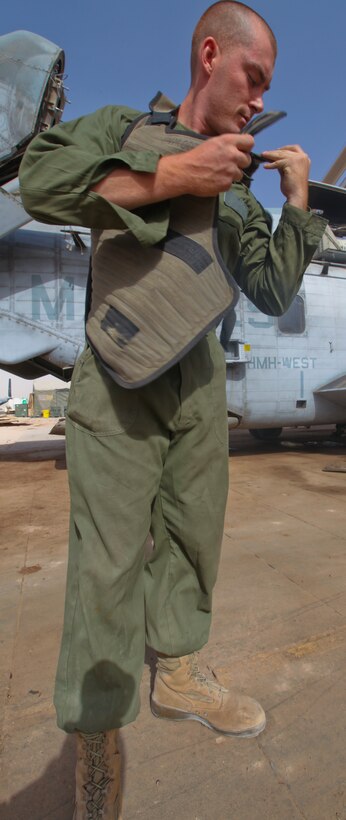 Lance Cpl. Jeffrey Wyman, a flight equipment technician with Marine Heavy Helicopter 361, 3rd Marine Aircraft Wing (Forward), finishes strapping on a Micro Climate Cooling Unit System vest Sept. 4. The vest, made of a thin material laced with hoses that pumps cool liquid around the body, is strapped to the body with velcro straps on the shoulders and body of the vest.