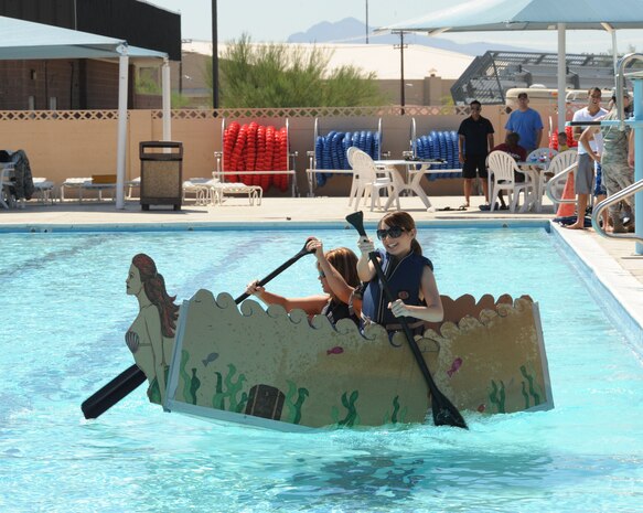 NELLIS AIR FORCE BASE, Nev.-- Jessica Garcia and Stephanie Stuart, representing the spouses of the 57th Aircraft Maintenance Squadron, paddle their way to the finish line during the Build-A-Boat competition Sept. 2. (U.S Air Force Photo by Senior Airman Stephanie Rubi)