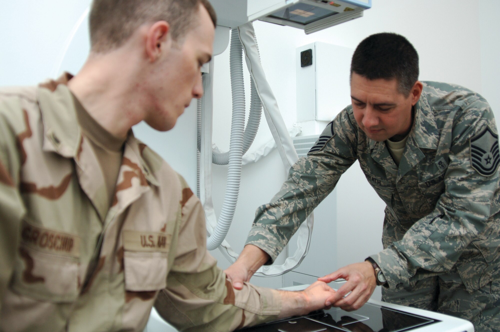 Master Sgt. Bruce Milbrath, 379th Expeditionary Medical Group radiology technician, prepares Petty Officer 3rd Class Matthew Groschup for a hand X-ray. (U.S. Air Force photo/Tech. Sgt. Kimberly Spinner) 