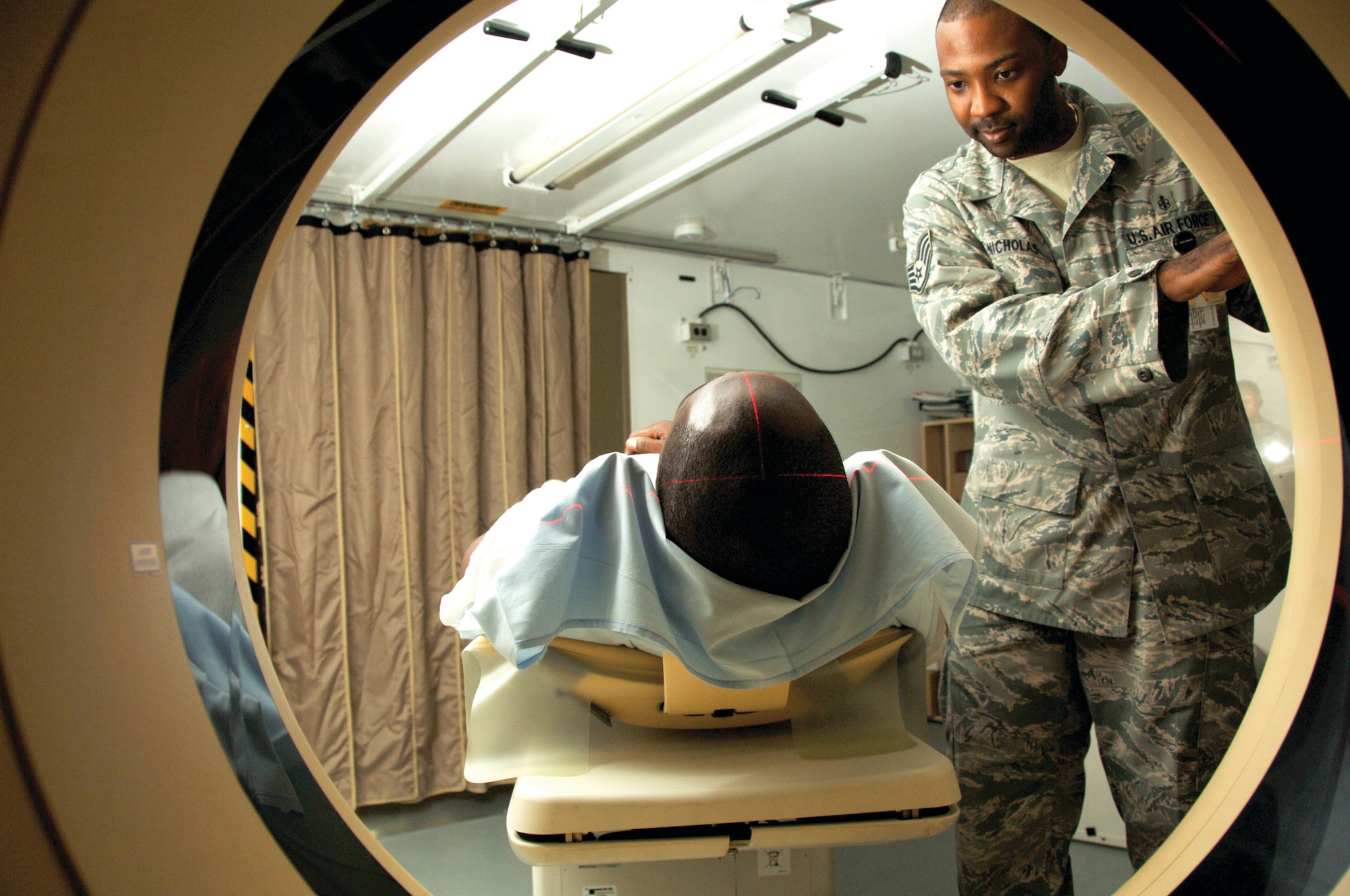 Staff Sgt. Jahmal Nicholas, 379th Expeditionary Medical Group radiology technician, prepares a patient for a computed tomography scanner. (U.S. Air Force photos/Tech. Sgt. Kimberly Spinner) 