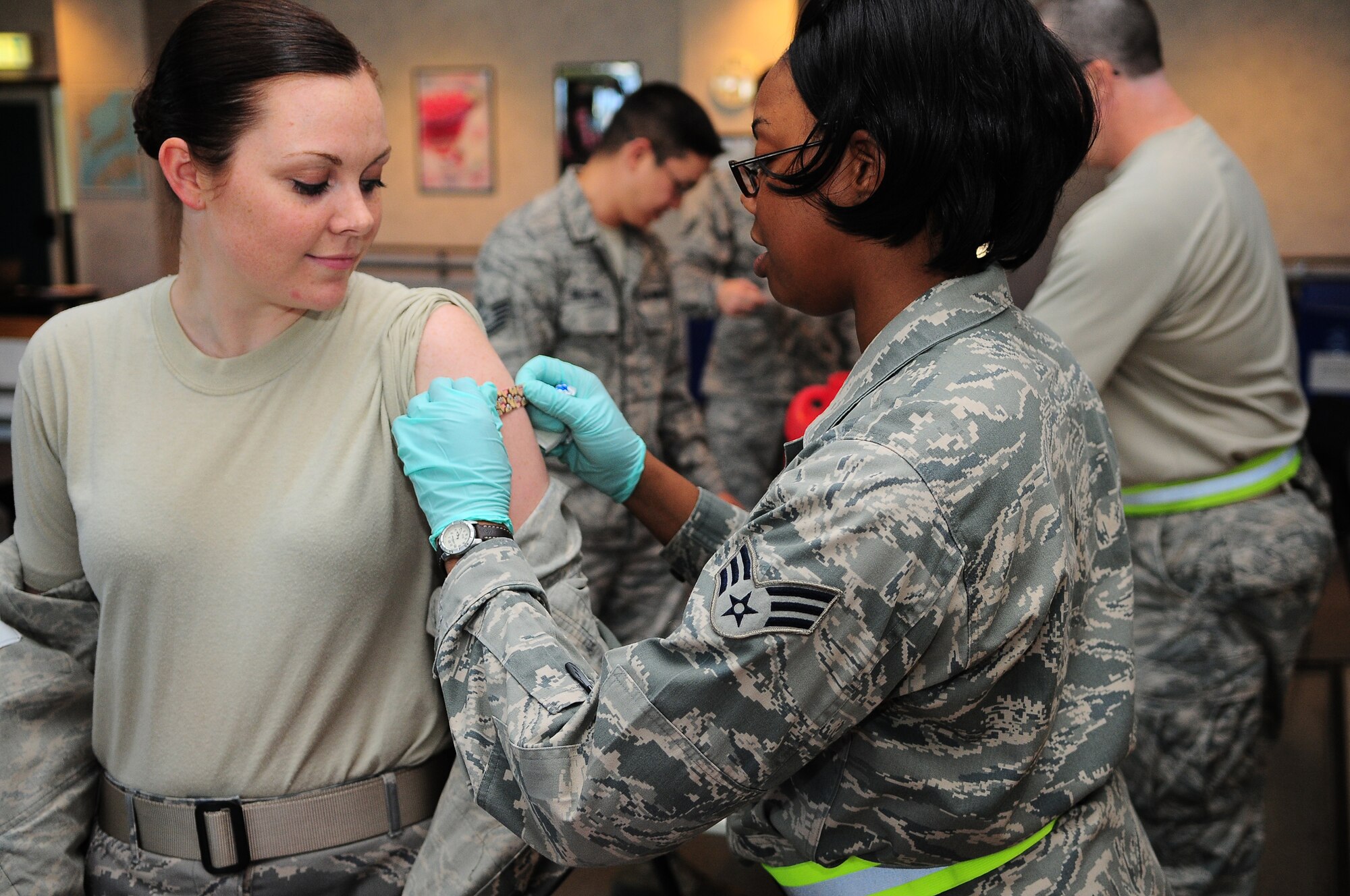 YOKOTA AIR BASE, Japan -- Senior Airman Tiffany Roberts, an allergy/immunization medical technician from the 374th Medical Operations Squadron, puts a band-aid on Airman Joyce Bray, from the 374th Security Force Squadron. Medical personnel set up at the Airmen and Family Readiness Center, here September 7, as a part of a Point of Distribution plan to vaccinate a large portion of the active duty population. Both the flu and H1N1 vaccines were available in either nasal or inject-able administrations. (U.S. Air Force photo by: Staff Sgt Stacy Moless)