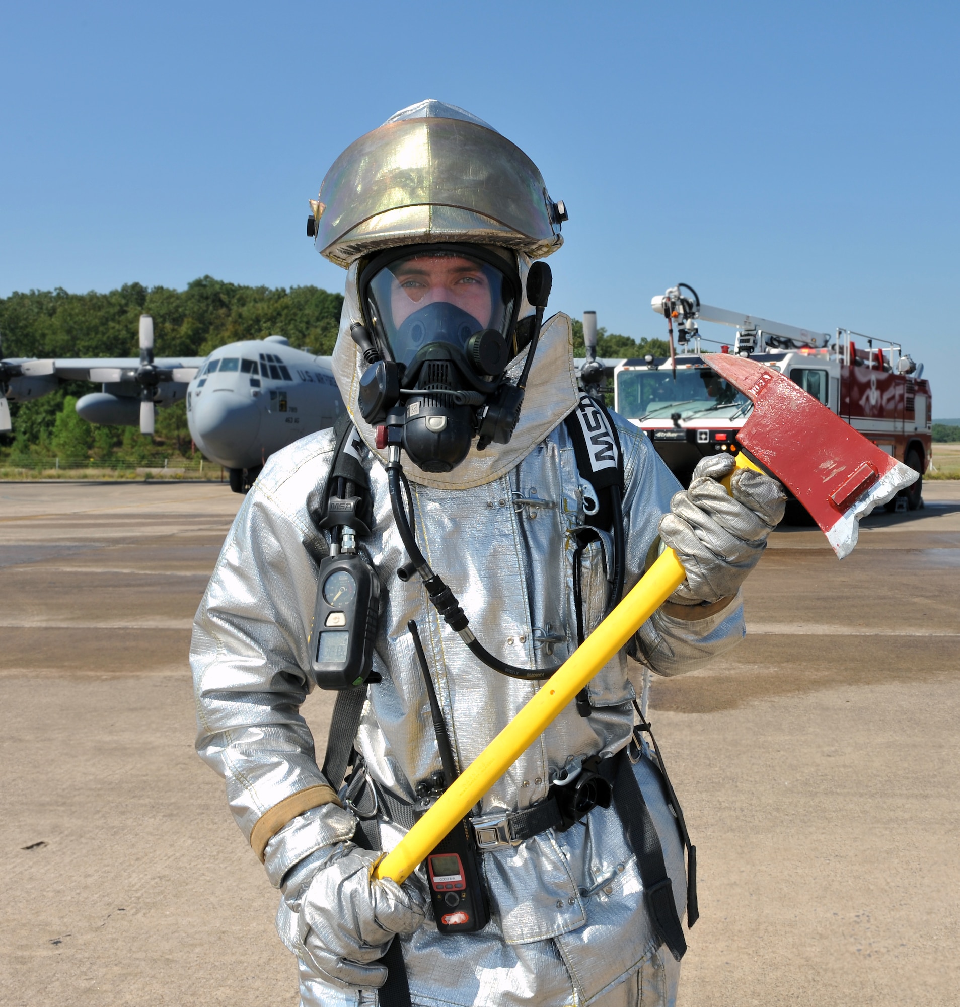 Staff Sgt. Benjamen Morin, 19th Civil Engineer Squadron fire protection crew chief, holds a fire axe designed for aircraft rescue Aug. 24 in front of a C-130E and a P-19H fire truck on the base flight line. The fire department motto is “the desire to serve, the ability to perform, and the courage to act.” (U.S. Air Force photo by Staff Sgt. Chris Willis)