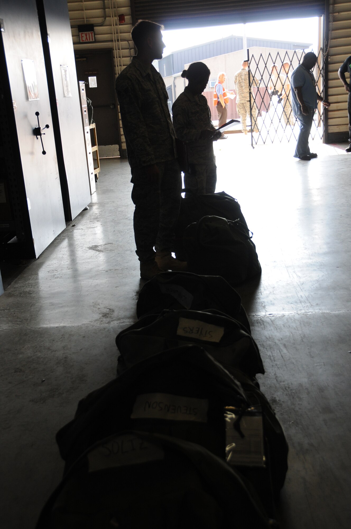 Senior Airman Joseph Jahnke, left, and Airman 1st Class Porsha Hazzard, 81st Security Forces Squadron, wait near a line of mobility bags during a deployment exercise Aug. 26.  Keesler also tested its response to a major accident scenario Aug. 25 involving a leaking fuel truck that caught on fire and injured the driver and 20 students.  (U.S. Air Force photo by Kemberly Groue)