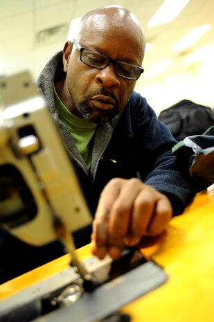 Isreal Middleton carefully adjusts and feeds thread through a sewing machine Sept. 1, 2010, on Joint Base Charleston, S.C. Using a sewing machine vastly increases productivity and accuracy and when dealing with expensive products and deadlines, every stitch counts. Mr. Middleton is a fabric worker with the 437th Operations Support Squadron. (U.S. Air Force photo/Senior Airman Timothy Taylor)
