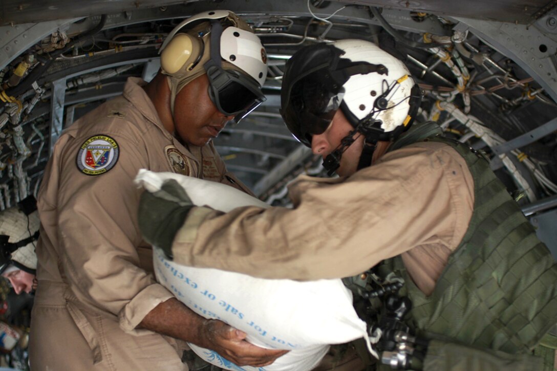 U.S. Navy Rear Adm. Sinclair Harris, right, assists U.S. Marines unload relief supplies from a CH-46 Sea Knight helicopter during humanitarian relief efforts in southern Pakistan, Sept. 4, 2010. The Marines are assigned to Marine Medium Helicopter Squadron 165, 15th Marine Expeditionary Unit. Harris is the representative for Office of the Defense Representative in Pakistan.