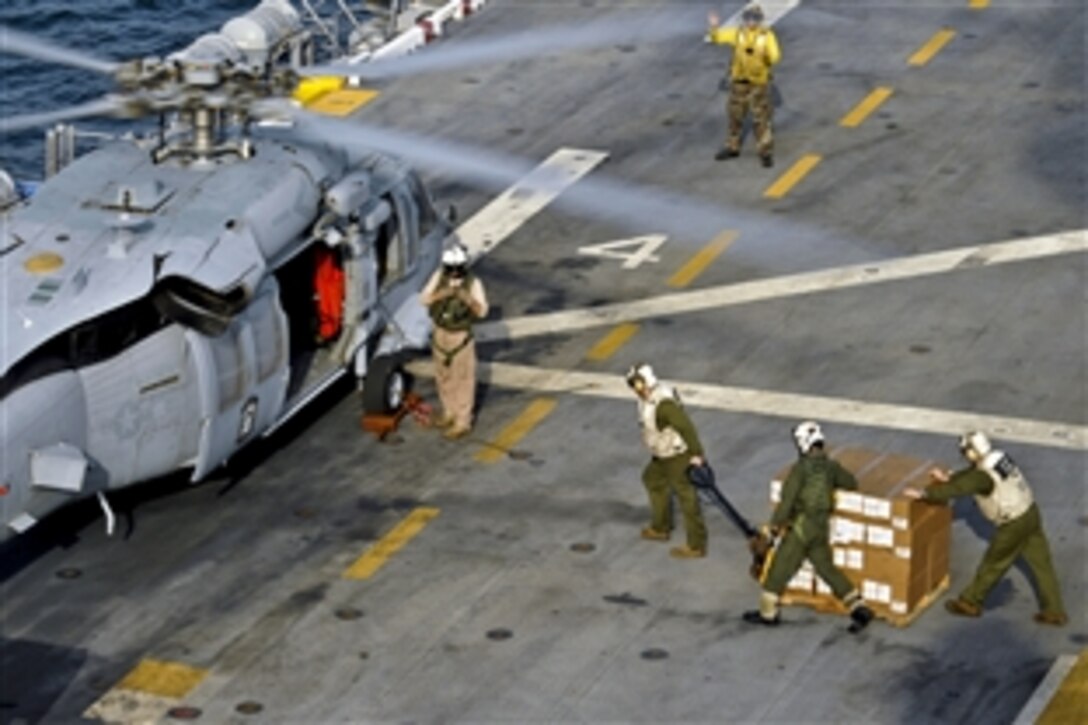 U.S. Marines and Navy sailors prepare to load disaster relief supplies onto an MH-60S Seahawk helicopter aboard the USS Peleliu in the north Arabian Sea, Sept. 6, 2010. The Peleliu is sending an initial supply of 80 pallets to Sharea Faisal Air Base, Pakistan, to distribute to the flood regions. The Marines are attached to a combat cargo unit and the sailors are attached to Helicopter Sea Combat Squadron 23.