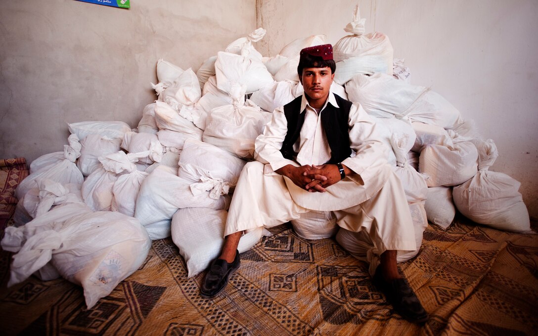 Hayatullah, one of the Nawa District governor’s bodyguards, sits atop food donations at the Nawa District governor’s Marine house near the Nawa District Governor’s Center, Afghanistan, Sept. 8, 2010. Making purchases through local suppliers, to be distributed to needy families in Nawa for the Muslim holiday Eid al-Fitr, a celebratory feast marking the end of Ramadan, 3rd Battalion, 3rd Marine Regiment, and the 3rd Civil Affairs Group purchased almost 4,000 pounds of food, enough to supply 130 families with a care package.