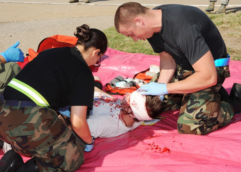 Senior Airman Zuleyma Perez-Rodriguez and Senior Airman Thomas Haney, 22nd Aerospace Medical Squadron medical technicians, provide emergency medical care to an accident victim during a Major Accident Response Exercise Sept. 1, 2010, McConnell Air Force Base, Kan.  After evacuating the “casualties” from the simulated crash site, they were placed in a triage area where their injuries were evaluated by Airmen of the 22nd Medical Group.  The volunteers who played victims held a slip of paper to help the firefighters and medics identify their medical conditions.  (U.S. Air Force photo/Airman 1st Class Andrea Salazar)